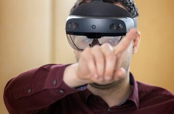 Nahaufnahme von einem Mann mit VR-Brille, der einen Finger nach vorne streckt