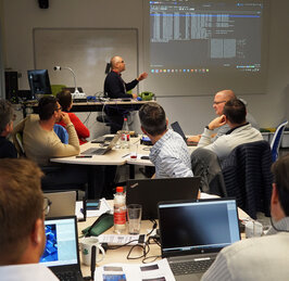 A group of teachers sitting at a desk listening to a lecturer